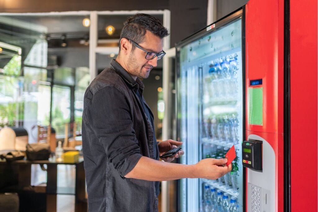 Man using a modern vending machine with a contactless payment card in a corporate office setting